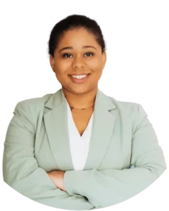 Woman with an olive colored blazer, smiling, and crossing her arms.