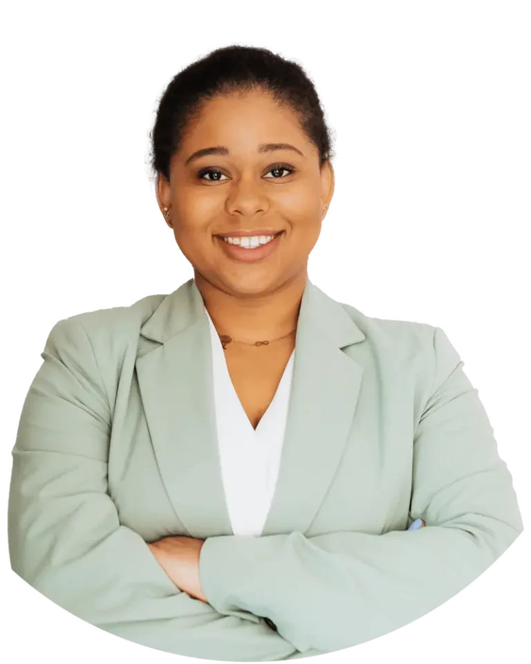 Woman with an olive colored blazer, smiling, and crossing her arms.