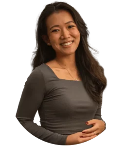 Woman with a grey shirt standing up, and smiling.